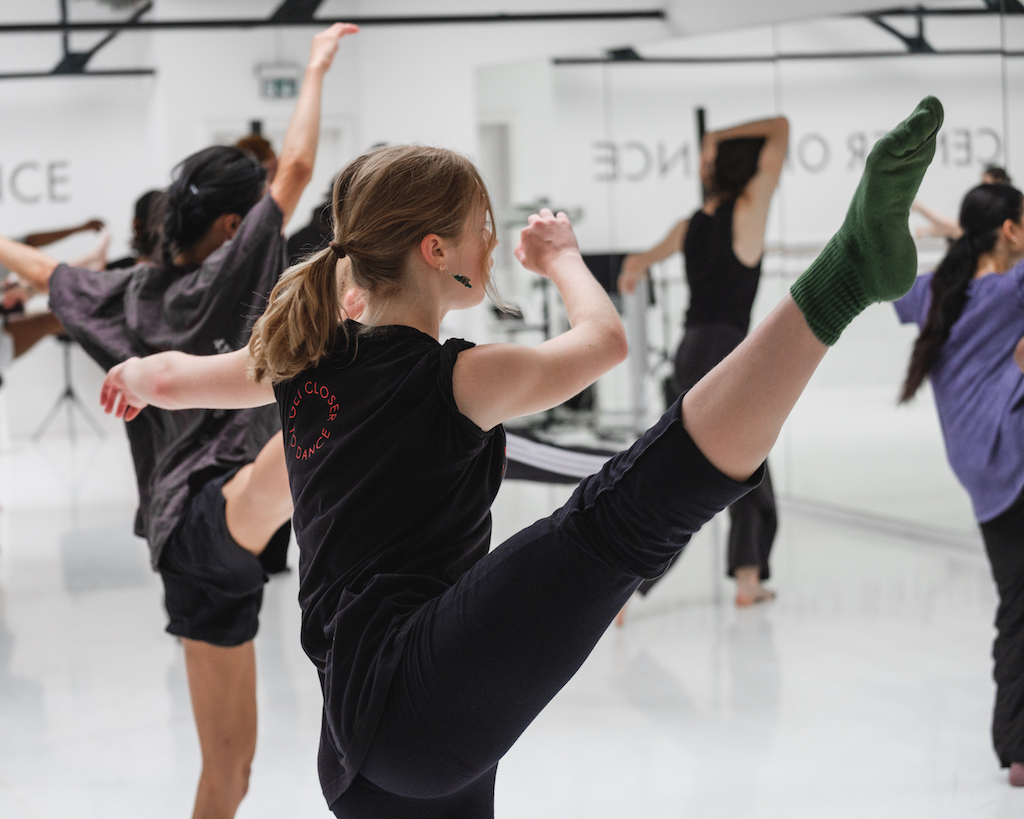 Dancers extend their legs and point their toes in mid-rehearsal